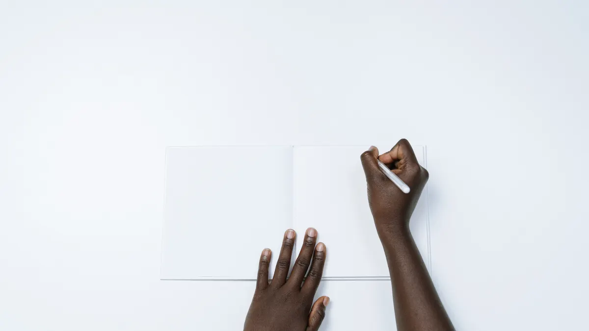 Hands writing in an open blank journal