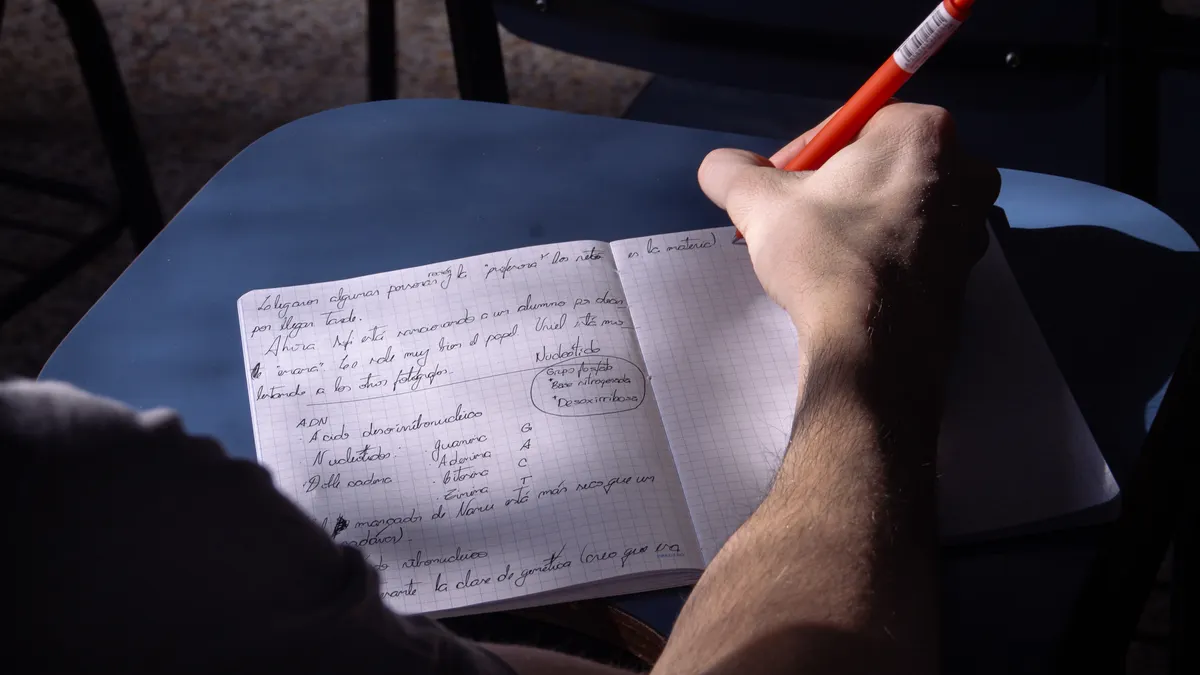 person writing in an open journal notebook