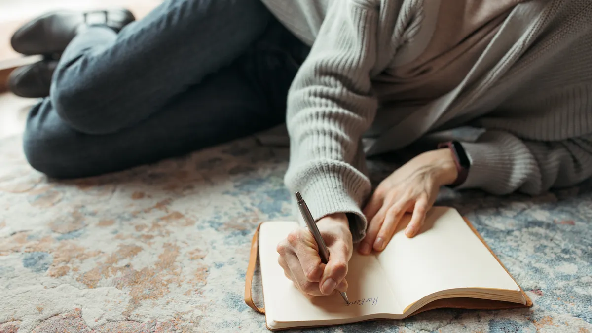 Person lying on the floor writing in an open journal