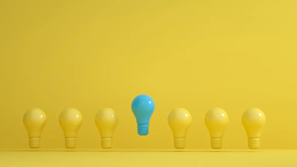 One blue light bulb among yellow bulbs on a yellow background