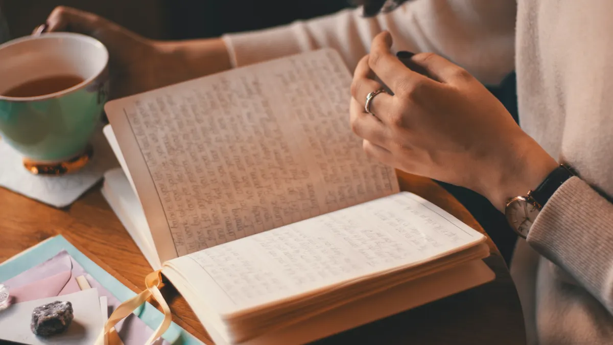 person journaling at a table beside a cup of tea