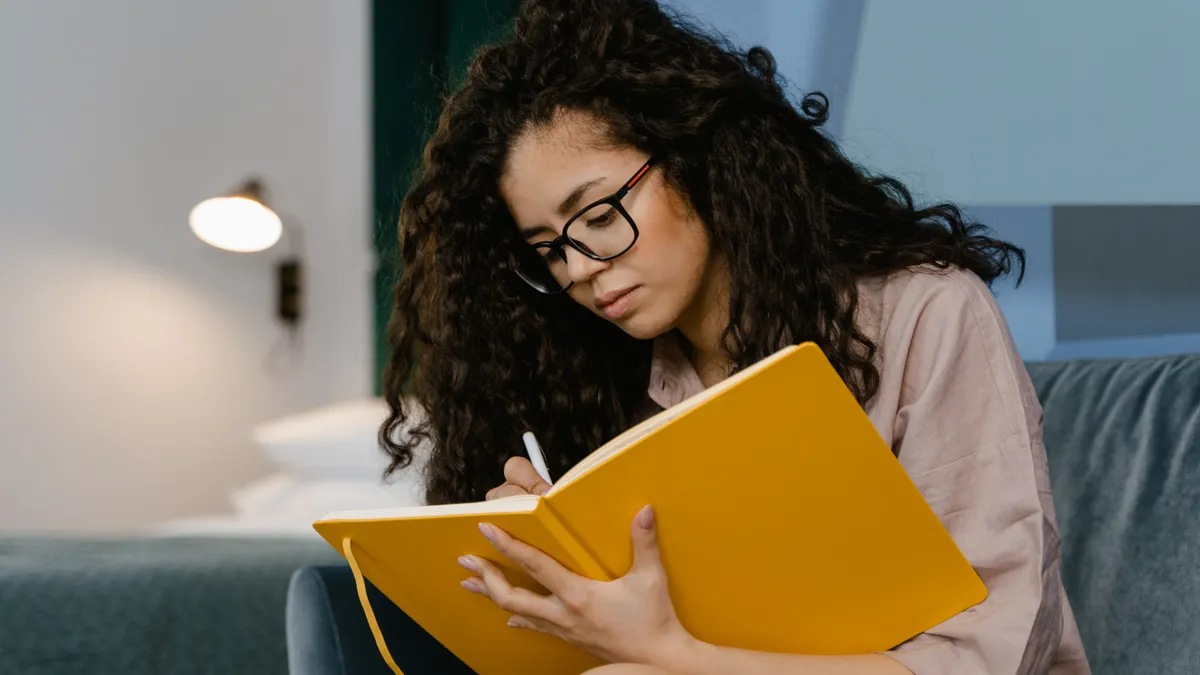 Woman writing in a bright notebook while reading