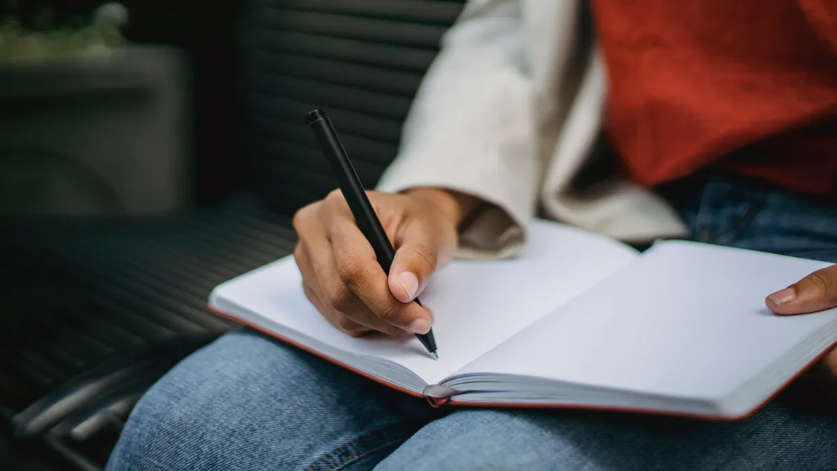 person writing in an open journal on their lap