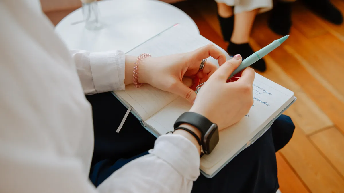 paper notebook with smartphone in hand